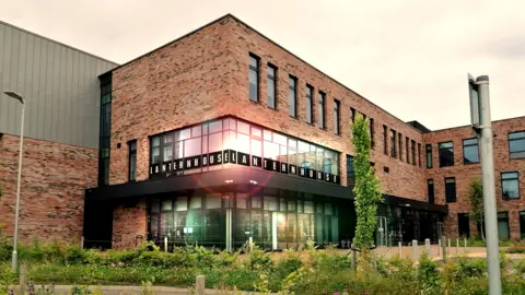 The outside of Cumbernauld Theatre. It is a modern, red brick building with large windows. 