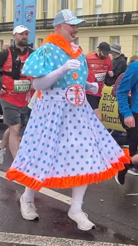 A man in a spotted dress running the half marathon