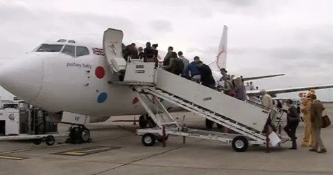 Passengers boarding a white aircraft from the front steps
