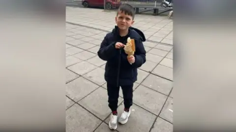 Family photograph Archie holding an ice cream. He wears a dark coloured coat.