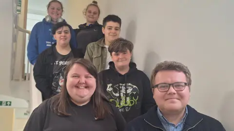 A group of young people standing on stairs, smiling.