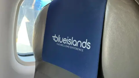 BBC A grey plane headrest with the Blue Islands logo on it.