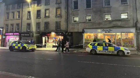 Two police cars parked next to the entrance of an alleyway on Nicolson Street in Edinburgh.