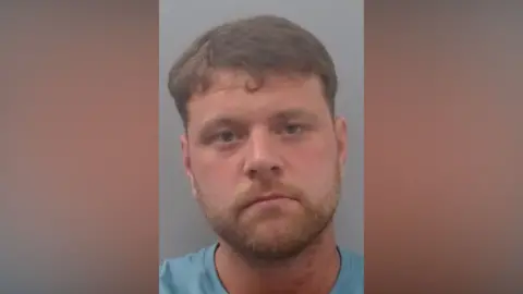 Mugshot of Pickering. He has gingery stubble and short thick brown hair