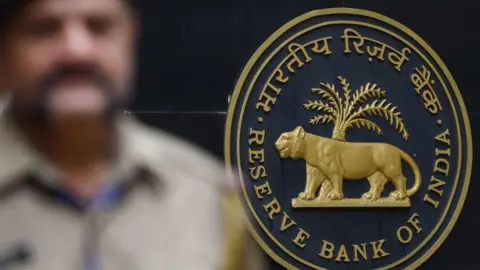 AFP via Getty Images A security staff walks past the logo of Reserve Bank of India (RBI) at the RBI headquarters in Mumbai. 