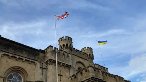 The Ukrainian flag and Union Jack flying from poles on the top of Oxfordshire County Hall.