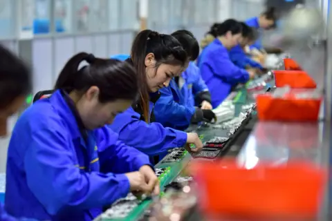 Costfoto / NurPhoto via Getty Images Women workers on a production line in a factory in Fuyang, China adjust circuit breakers while wearing blue overalls, pictured on 4 March.