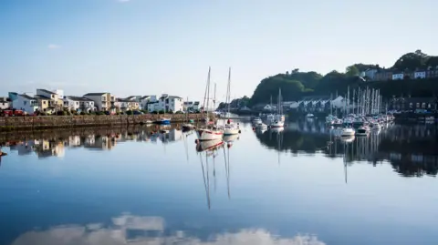 Getty Images A wide image of the reflections on the calm waters of Porthmadog Harbour.