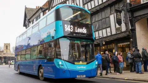 A blue Coastliner double decker bus in York. The sign says '843 Leeds'