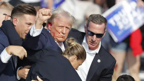 EPA Donald Trump pumps his fist after being grazed in the ear when a gunman fired shots during his rally