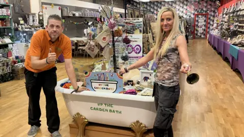 Shariqua Ahmed/BBC Dave Poulton with his partner posing in front of an upcyled white bathtub