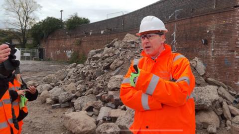 Labour West of England Mayor Dan Norris wearing hi vis and a hard hat with his thumb up