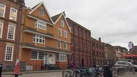 An exterior view of the Partou Nursery building on King Street. It is an orange building with four floors. It has white windows and white doors with a few steps up to them.