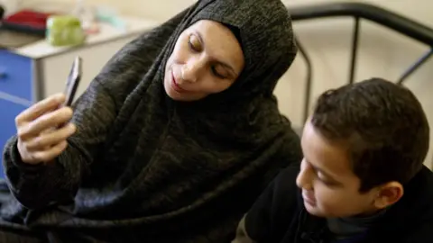 A boy and his mother look at a mobile phone