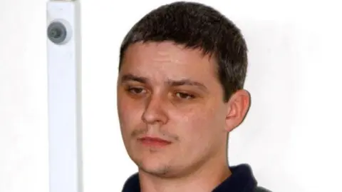 Ian Huntley, de PA Media: un hombre con cabello corto y oscuro y una ligera barba incipiente. Lleva pantalones cortos oscuros con cuello.
