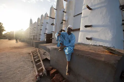 MEHMET ASLAN / ANADOLU / GETTY IMAGES A man sits at the outside the Grand Mosque.