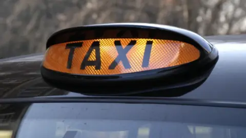 A black cab orange light, atop a vehicle, can be seen close up in this image.