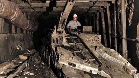 Stuart Porthouse Stuart underground at Woodhorn Colliery, wearing a miner's helmet with a light attached on top of mining equipment used down the pits.