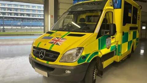 A yellow and green emergency ambulance with a Union Jack painted on the front, alongside the words "Driving Ukraine".