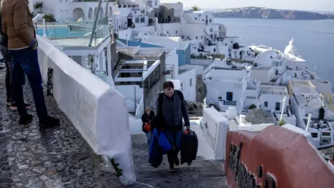 Reuters People leaving the Port of Fira carrying a suitcase 