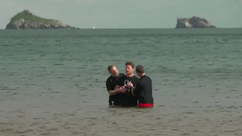John Wells in the sea with two reverends being baptised. 