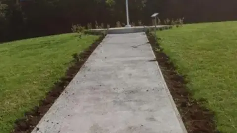 Royal Wootton Bassett Town Council A concrete path with upturned soil in a row along each side - holes can be seen when plants would once have been.