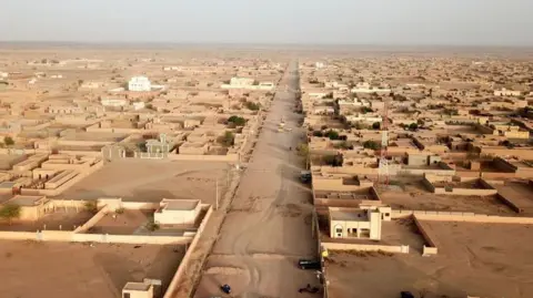 AFP via Getty Images An aerial shot of Kidal. The city looks like it is sandy and the buildings are the colour of sand