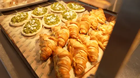 Pea and feta pita bread and scrambled egg croissants are lit up on a hot plate