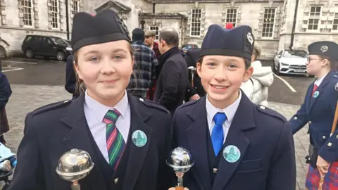 Molly Bell and Rosie McKinstry are both wearing navy uniforms and hats and both have dark hair tied back 