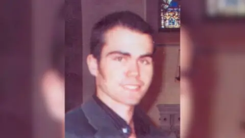 PSNI Martin Kelly smiling at the camera, he has dark hair and dark clothing on.