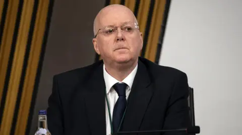 Getty Images Peter Murrell wearing a dark suit over a white shirt and black tie.