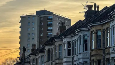 Getty Images The sun sets behind a block of flats and a row of terraced houses in Bristol.