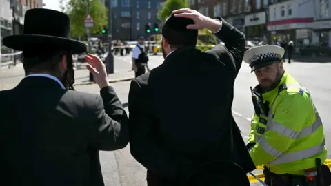 Getty Images Two Jewish men and a police officer
