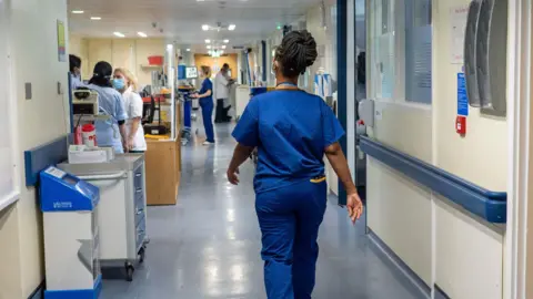 PA Media Medical worker walking down a hospital corridor