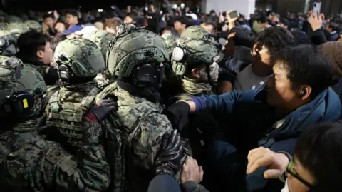 Getty Images Soldiers in combat uniform clash with a crowd of citizens