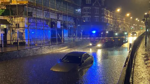 London Fire Brigade A car partly submerged in floodwater on Manor Road in Wallington