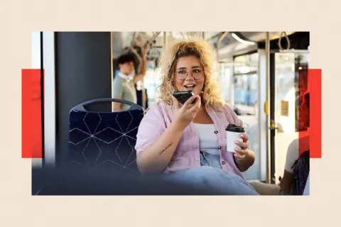 Getty Images A woman using her mobile on speakerphone on a bus while holding a coffee
