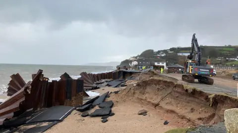 The A379 Slapton Line between Torcross and Slapton. An excavator and workers can be seen as well as twisted bits of metal. 