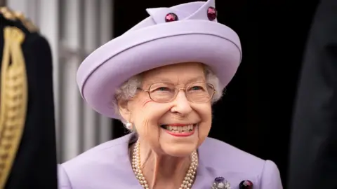 Image of the late Queen Elizabeth II smiling at an event at the Palace of Holyroodhouse, dressed in lilac.