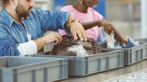 People placing bags on airport security conveyor belts 