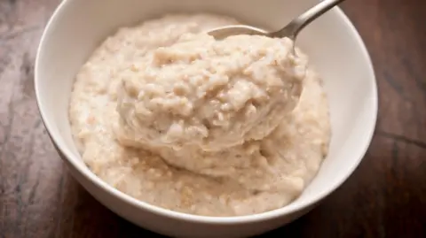 Getty Images Gros plan d'un bol de porridge avec une cuillère sur une table en bois