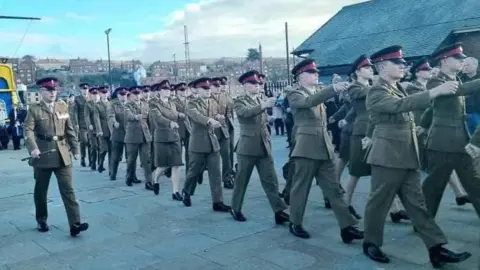 A procession of people in green Army uniforms.