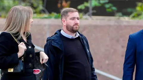 PA Media David Chambers, with brown facial hair and wearing a dark blue jumper over a blue shirt, walks away from Liverpool Crown Court