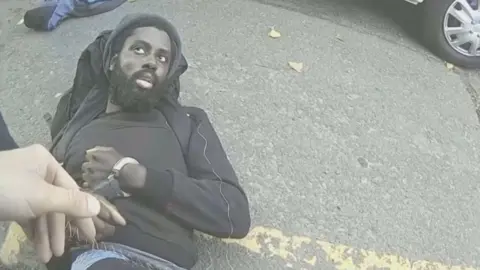 Nottinghamshire Police An image taken from police body-worn camera footage of the moment Calocane was arrested on 13 June 2023. He is laying on his back on the floor and being put in handcuffs.