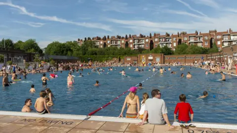 Getty Images Parliament Hill Lido, London pictured in the modern day. The pool is very busy with hundreds of people enjoying the lido. 