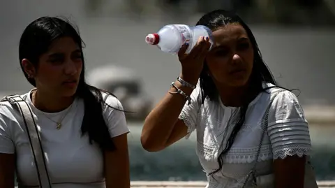 Getty Images A woman places a bottle filled with ice on her head to cool down at St Peter's Square in the Vatican