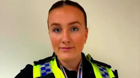 PC Rhona Adams, who has dark hair pinned back. She is wearing a police officer's uniform.