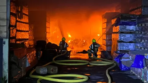 Surrey Fire and Rescue Service Firefighters tackle the fire which is seen burning inside a building