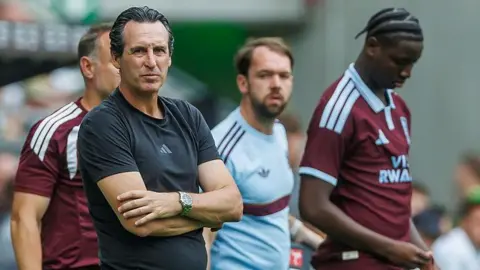 Unai Emery in short-sleeved dark T-shirt with arms folded