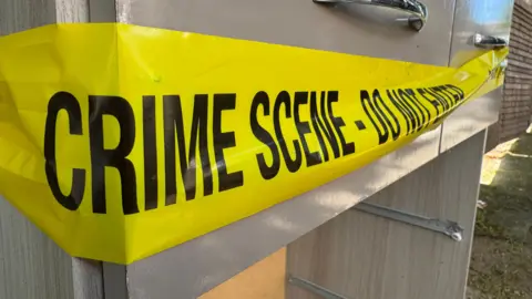 Gabby Colenso/BBC A chest of drawers stands in a street with yellow crime scene tape around it.